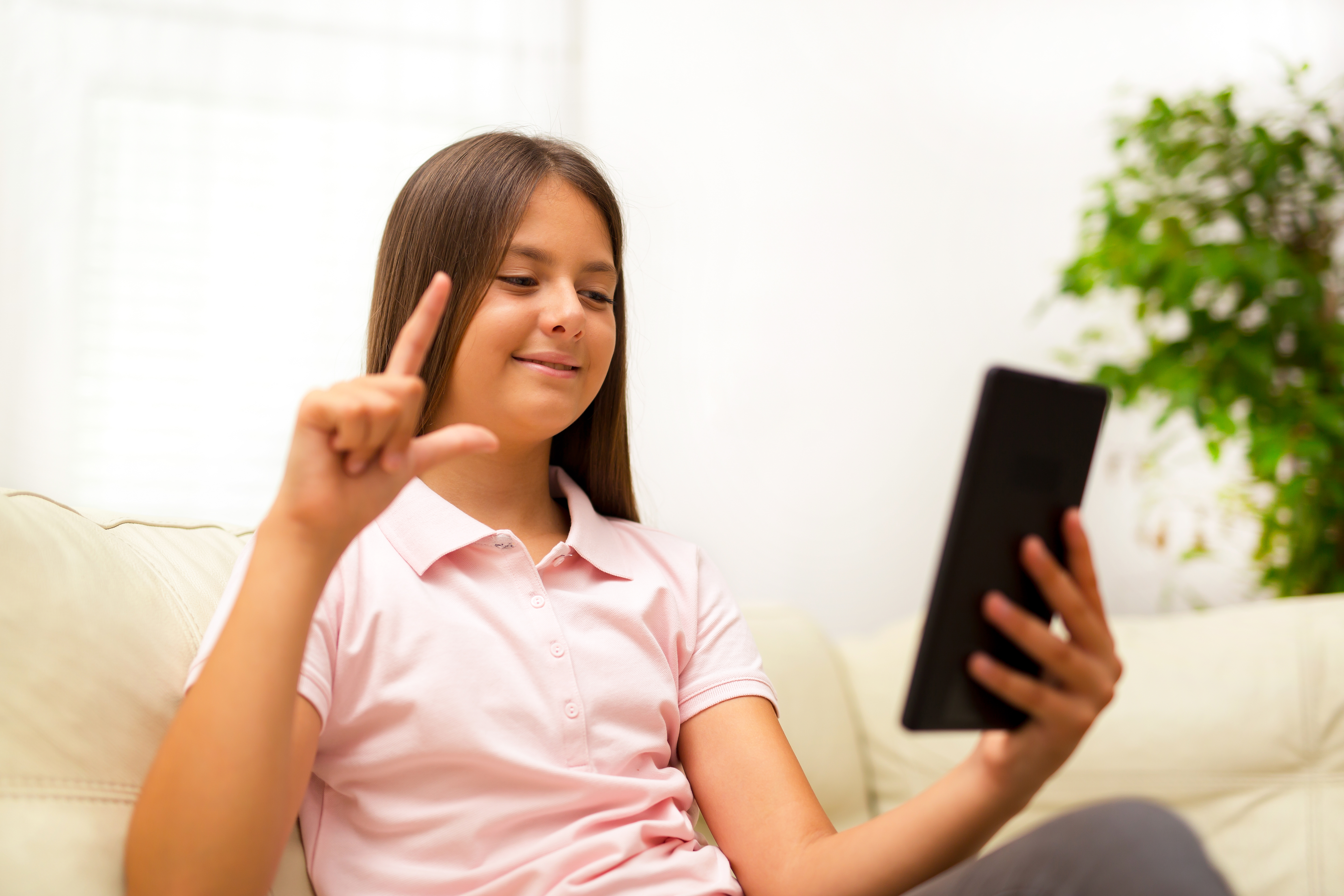 Smilende jente bruker tegnspråk på nettbrettet