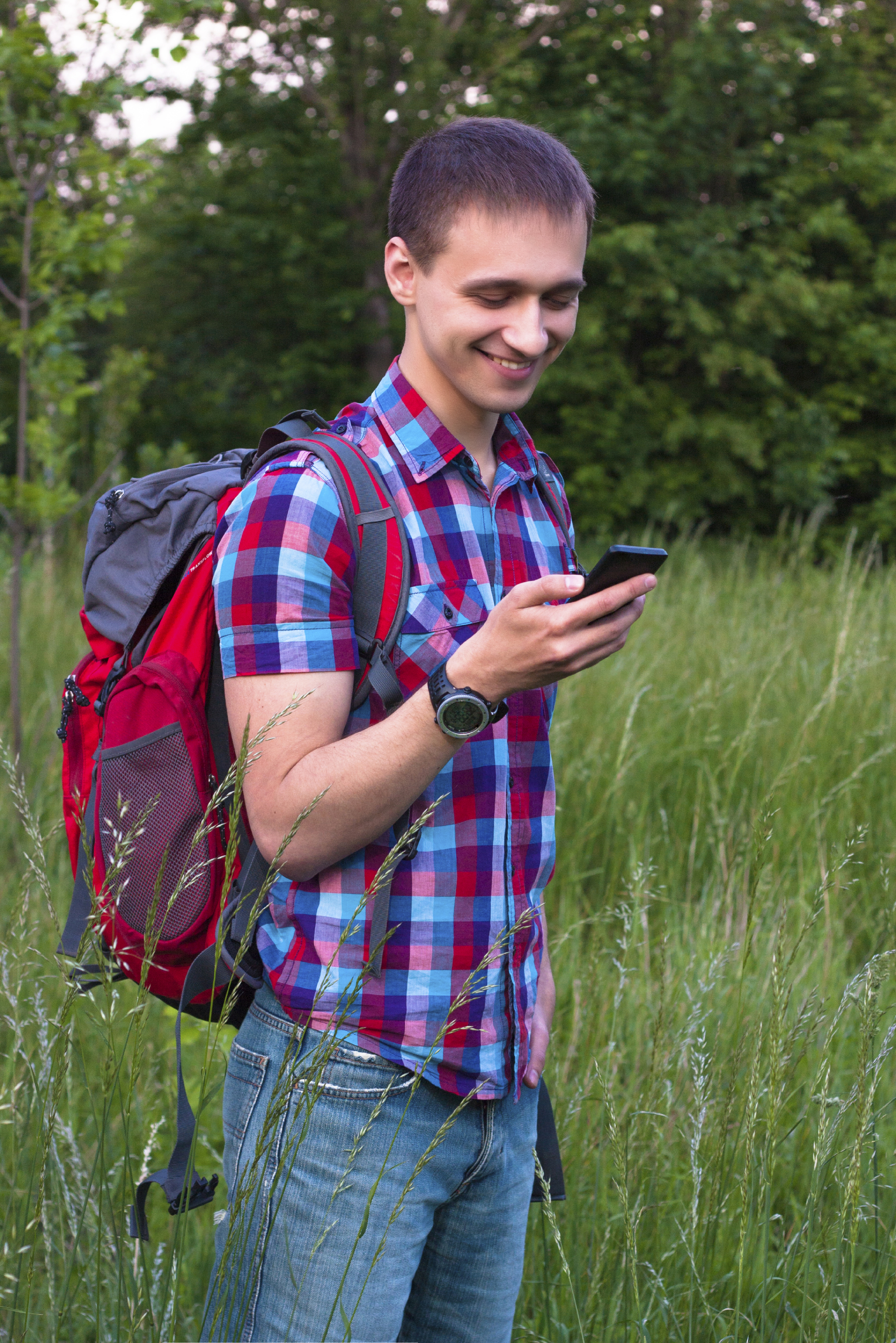 Gutt med smarttelefonen sin i skogen. Han leter etter en geocache.